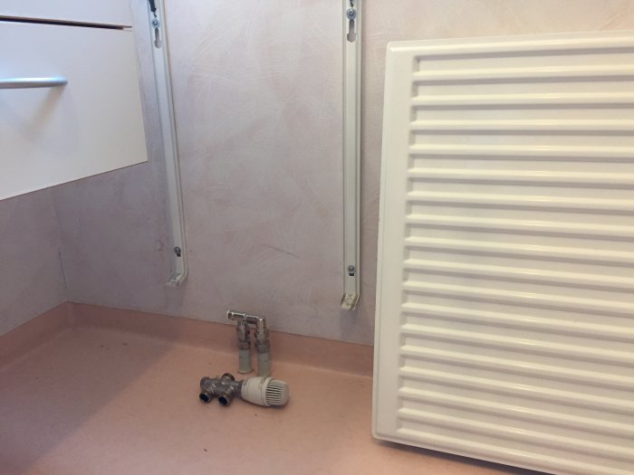 Radiator bredvid avmonterade rör och en ventil, tecken på förberedelse för byggprojekt.