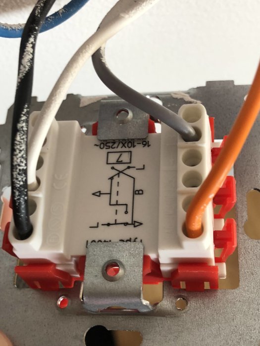 Elektrisk koppling med vit, svart och orange kabel ansluten till en strömställare mot vit bakgrund.