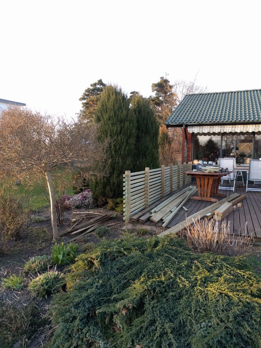 Trädgård med odlingslådor i konstruktion och material för altanräcken, nära en veranda.