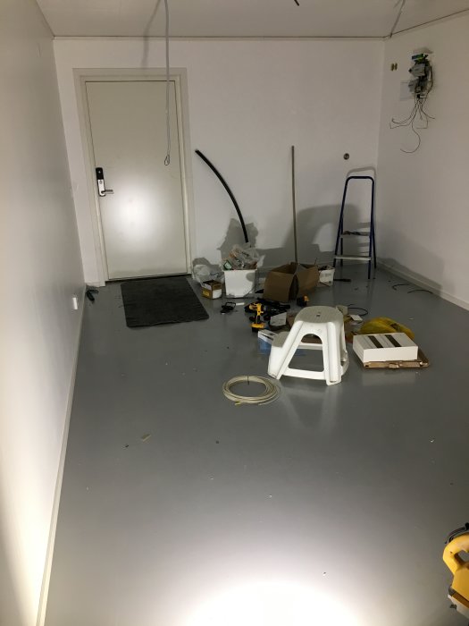 Nymålat golv i ett rum under renovering med verktyg och målningsmaterial utspridda.