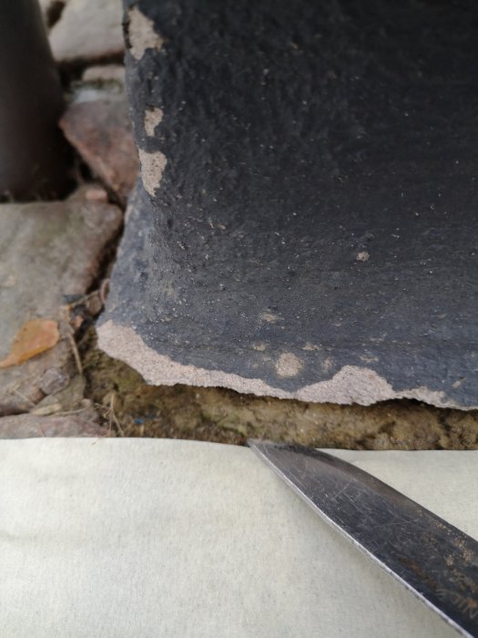 Närbild på betongsula med synlig isolering och en kniv som pekar på exponerat område.