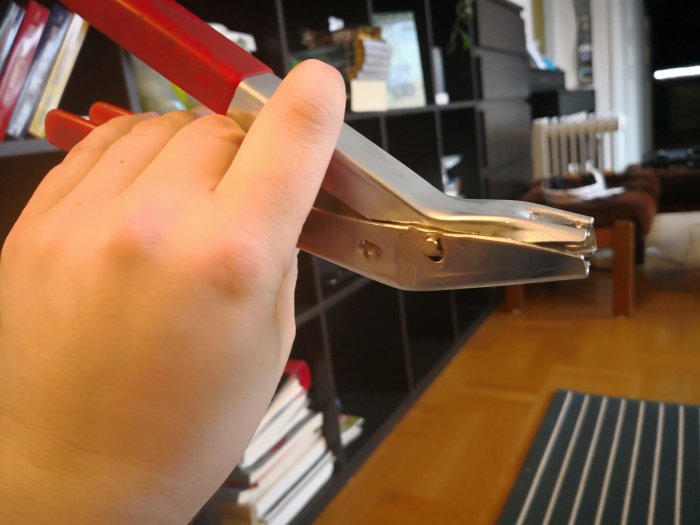 Hand håller slitna metalltång för att dra ihop expandrar.
