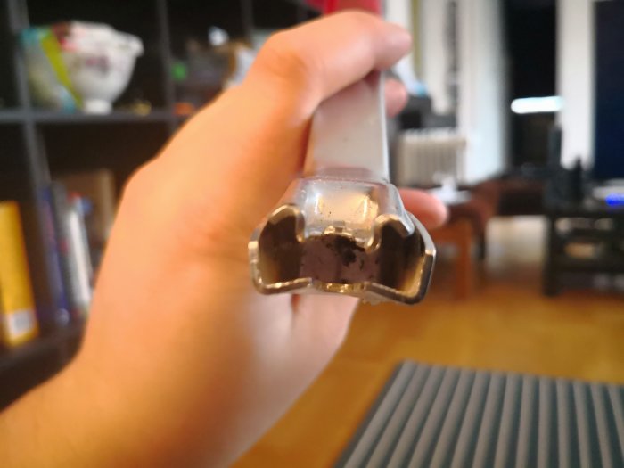 Hand håller ett slitet verktyg för att dra åt metallexpander, inomhus.