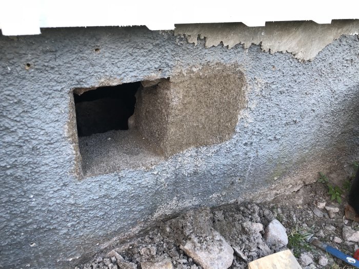 Reparation av grundmur med nytt lager cementbruk, med synligt hål och ojämn yta.