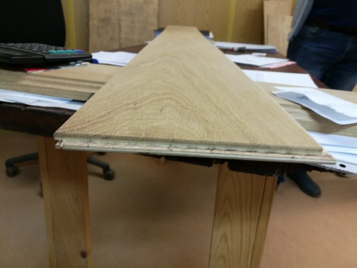 Ett kvistfritt ekgolv i fallande längder på ett bord i ett kontorsmiljö.