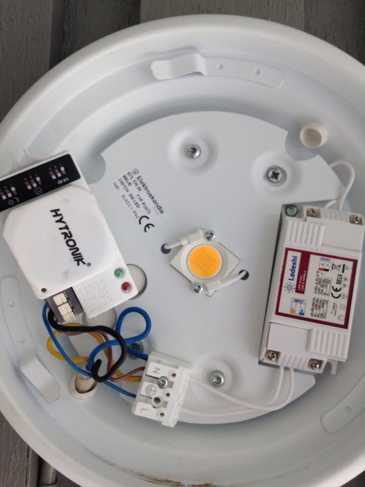 Öppen utelampa som visar en LED-modul, drivdon, och elektriska anslutningar.