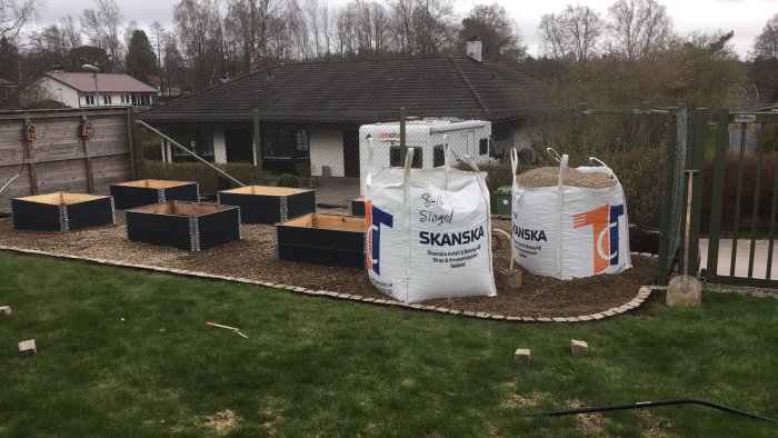 Trädgård med grusgång, odlingslådor och två stora säckar grus från Skanska.