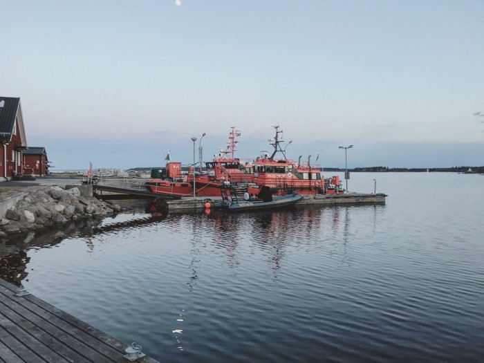 Lotsbåtar förtöjda vid en brygga i skymningen med lugnt hav och klart väder.