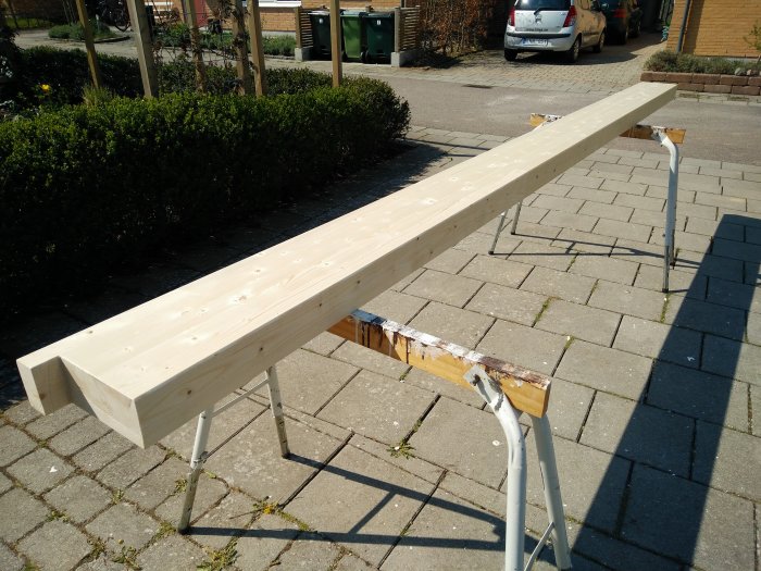 Nykapade träbärlinor placerade på sågbockar utomhus, redo för att bygga takstolar.