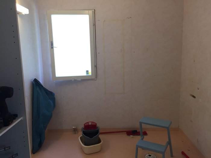 Tomt rum under renovering med borttagna badrumsinredningar och synliga rör på golvet.