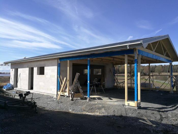 Nybyggt garage med anslutande carport under konstruktion, vädertätat, vid ett bostadshus.