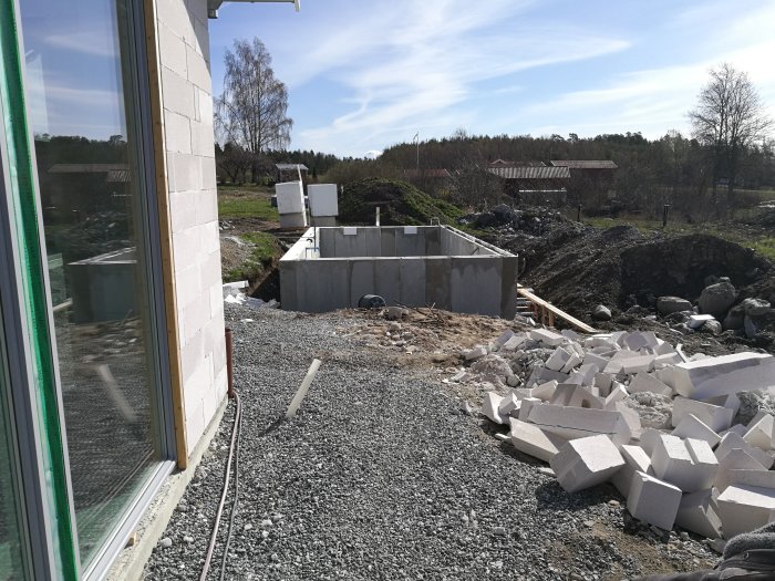 Nybyggd carport bredvid ett hus och en omonterad pool från Tjällden på en grusgrund.