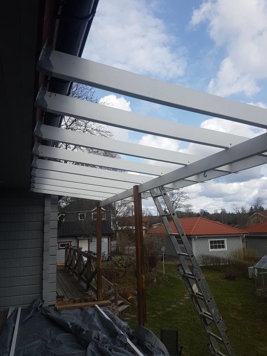 Delvis nedmonterat tak med vita takbjälkar och hängränna, en stege lutad mot huset.