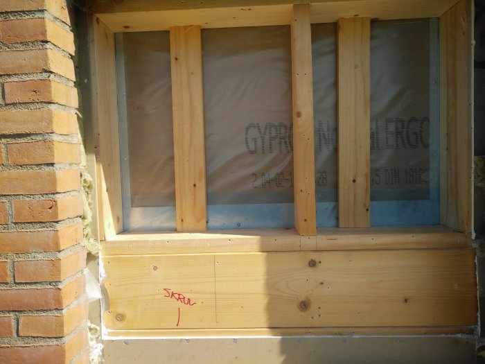 Nykapade träreglar monterade på en vägg i ett byggprojekt, med isolering skymtandes bakom.