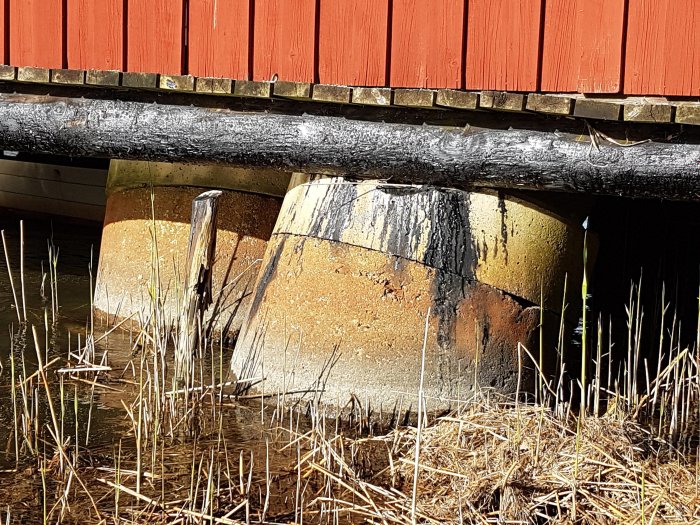 Skadade cementringar under båthus, med synliga sprickor och slitage orsakade av is.