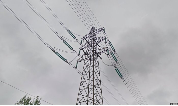 Högspänningsledning och mast mot grå himmel, som perspektivfrågande relaterar till närhet till bostäder.