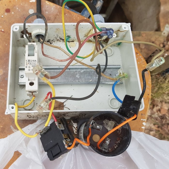 Öppen elektrisk kontrollåda med kablar, relä, kondensator och med säkring, placerad utomhus.
