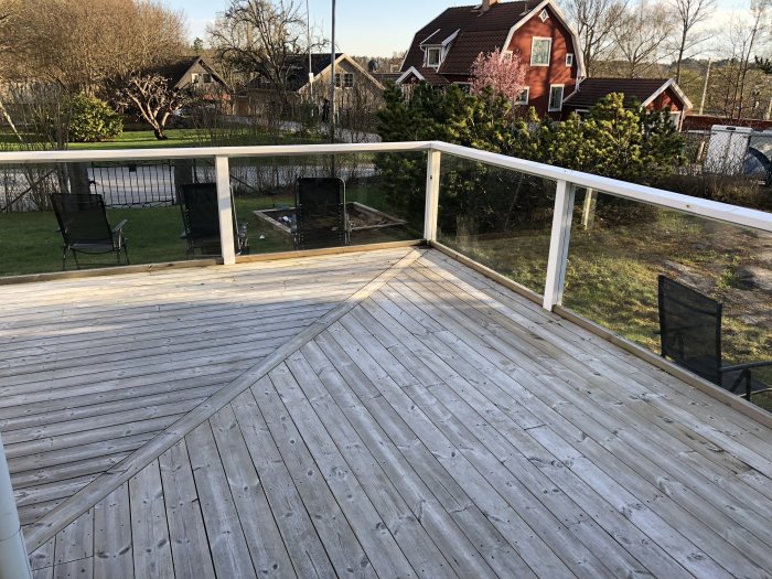 Trall av trä som är såpad och rengjord på ett altandäck med staket, stolar i bakgrunden.