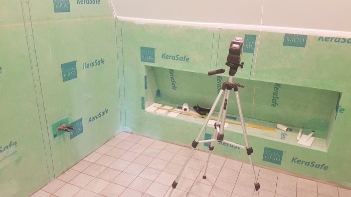 Tilltänkt nisch i vägg med halvkaklade ytor och lasersikte på ett stativ.