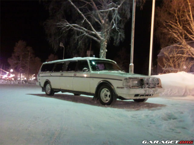 Vit förlängd limousine parkerad på en snötäckt gata på natten.