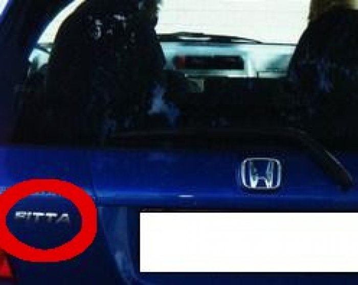 Blå bil med Honda-emblem och modellnamnet "Fitta" inom röd cirkel på bakluckan.