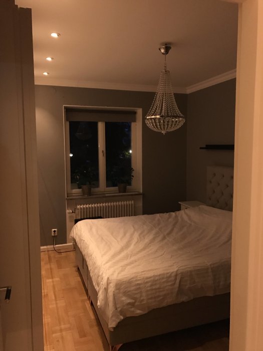 Elegant sovrum med nyinstallerade LED spotlights i taket och kristallkrona över sängen.