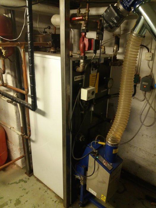 En värmepanna Euronom A25 Combi med en pelletsbrännare JanFire Flex-A i ett pannrum, rörledningar och expansionskärl syns.