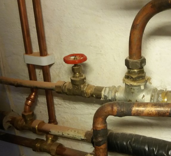 Kilslidsventil och röranslutningar i ett värmesystem, inklusive kopparledningar och isolering.