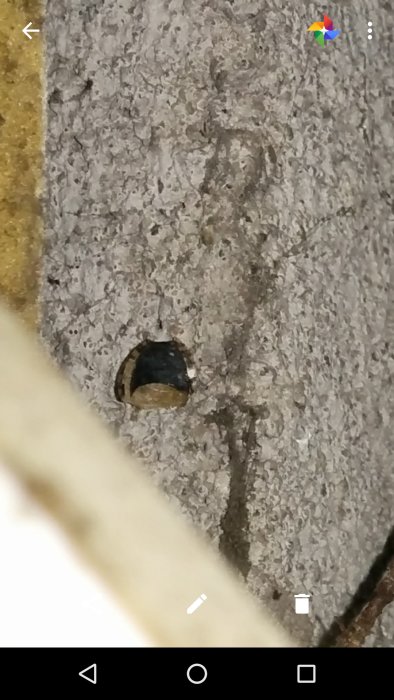 Närbild av grå betongvägg med synlig stålrörsknopp.
