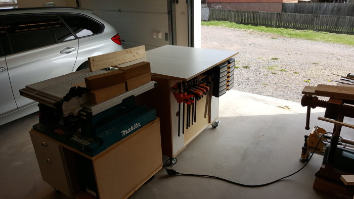 Utmatningsbord konverterat från ett gammalt skåp i ett garage vid sidan av träbearbetningsverktyg och en bil.