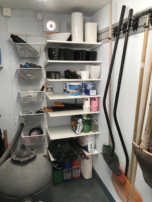 Organiserat garage med hyllor av återanvänd inredning och verktyg som hänger på väggen.