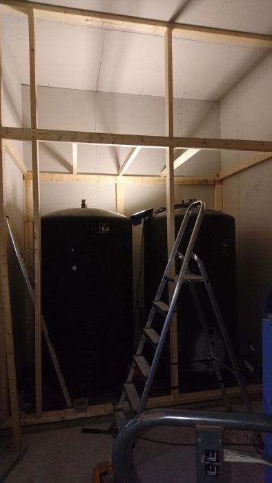 Två stora tankar i ett rum under konstruktion med trästomme och stege framför.