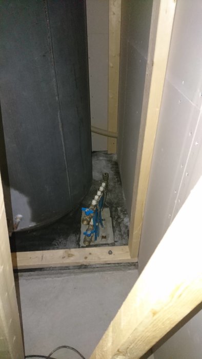 Installation av kulvertrör mellan tankar i trångt utrymme på ett betonggolv med delvis klinker.