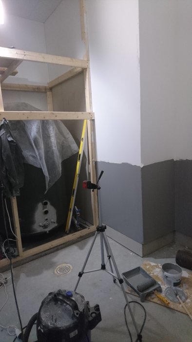 Halvfärdig renovering av badrum med osatt klinker, väggar delvis i trä och en stege.