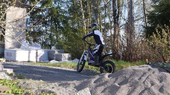 Person i skyddsutrustning och hjälm kör en begagnad Oset 20R eldriven motorcykel utomhus.