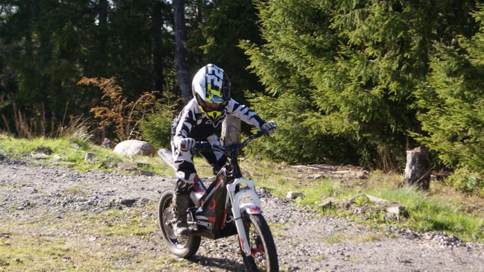 Barn på en begagnad Oset 20r motorcykel med hjälm och kläder i naturen.