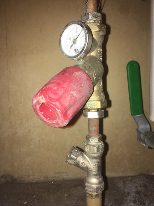 Värmesystemsventil märkt AHA med manometer och röd termostatknopp, cirkulationsledning.
