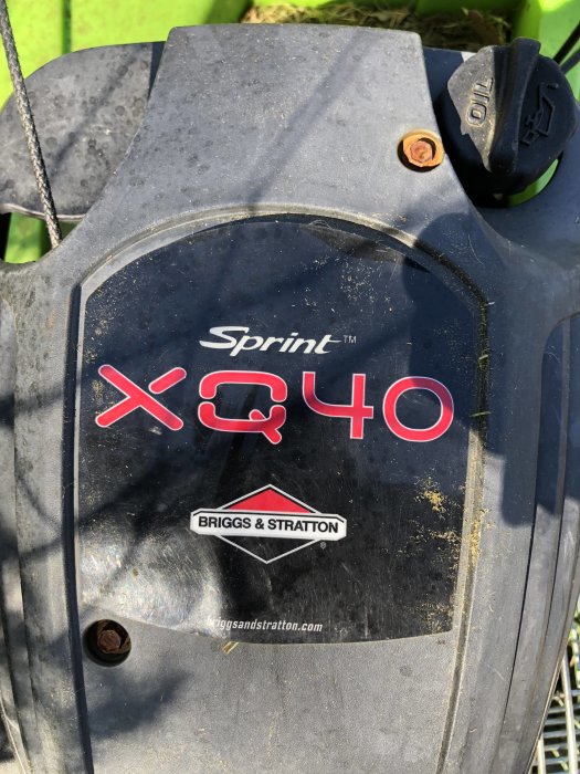 Närbild av en Briggs & Stratton Sprint QX40 motorhuv med tydligt logotyp och modellnamn.