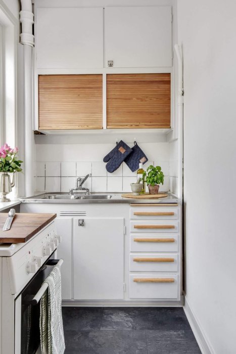 Renoverat kök med vita luckor, trädekor och moderna handtag, snyggt och välorganiserat.