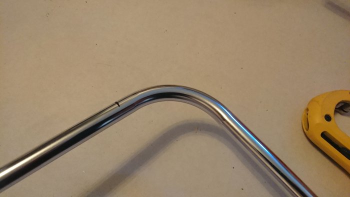 15mm kromat rör med 90° bock nära en markering och rörskärare i bakgrunden.