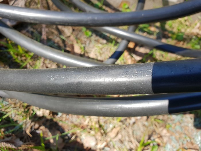 Nahaufnahme von Nexans N1XV 4x10 Kabeln im Freien mit sichtbarer Beschriftung auf der Isolierung.