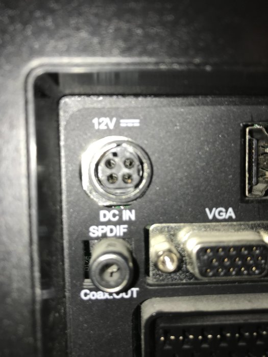 Närbild på en TV:ns bakpanel med 12V DC-ingång, SPDIF och VGA-kontakter, där DC-kontakten är i fokus.