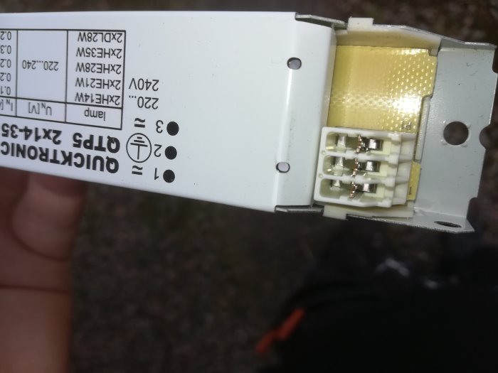 Närbild av en öppen elektronikenhet med synliga anslutningar och delvis läsbar etikett.