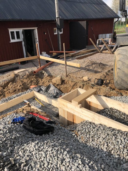 Preparations for concrete foundation with reinforcement bars, wooden formwork, and gravel on a construction site.