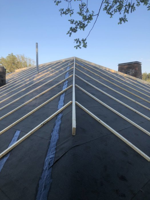 Monteringsprocess av träläkt och nockbrädor på ett tak under konstruktion.