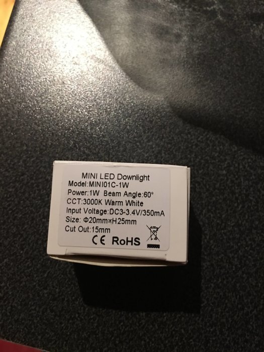 MINI LED Downlight etikett med specifikationer på en mörk texturerad yta.