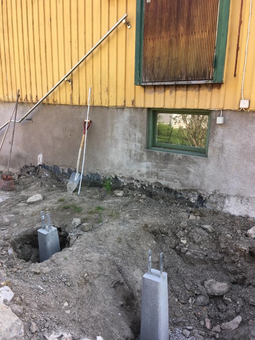 Grundläggning för entretrapp med nya betongplintar vid en husvägg med synliga markarbeten.