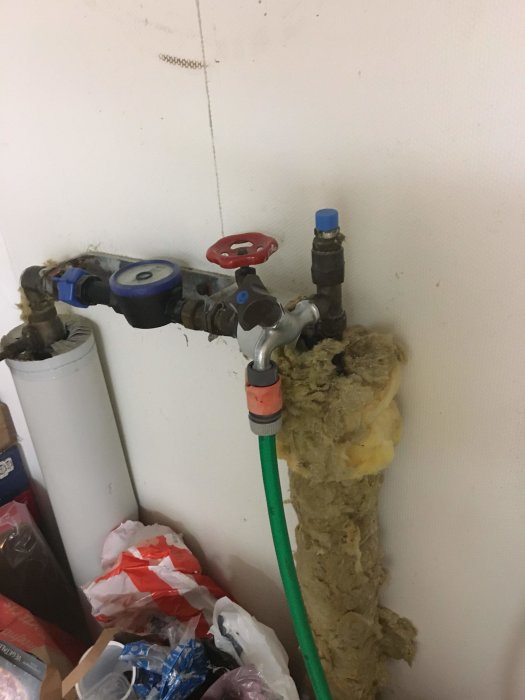 Vatteninstallation med T-rör, kranar, blå koppling och PEM-slang i ett hus.