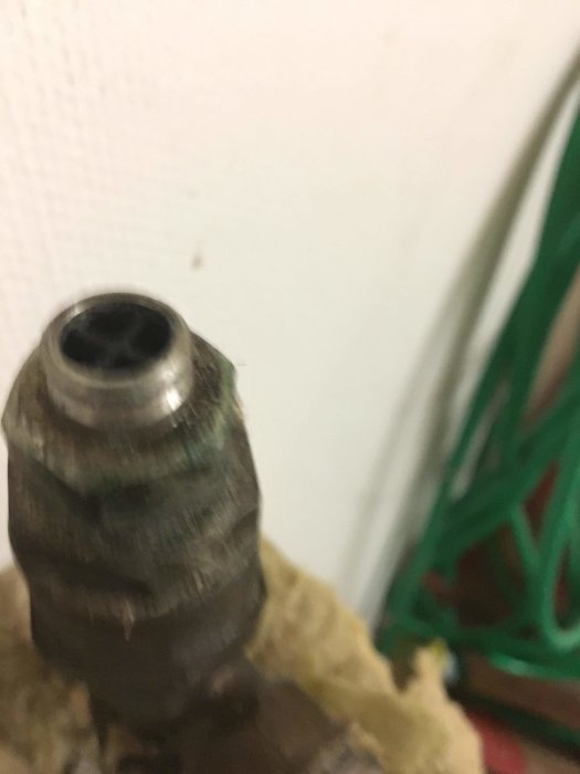 Oskarp närbild av en metallextremitet på ett rör, omgiven av isolering, med en suddig bakgrund.