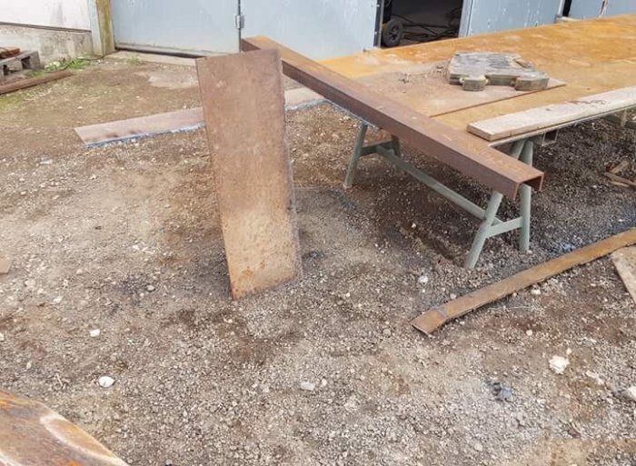 9mm tjock plåt skuren med skärbrännare står på grusmark vid arbetsbänk utomhus.